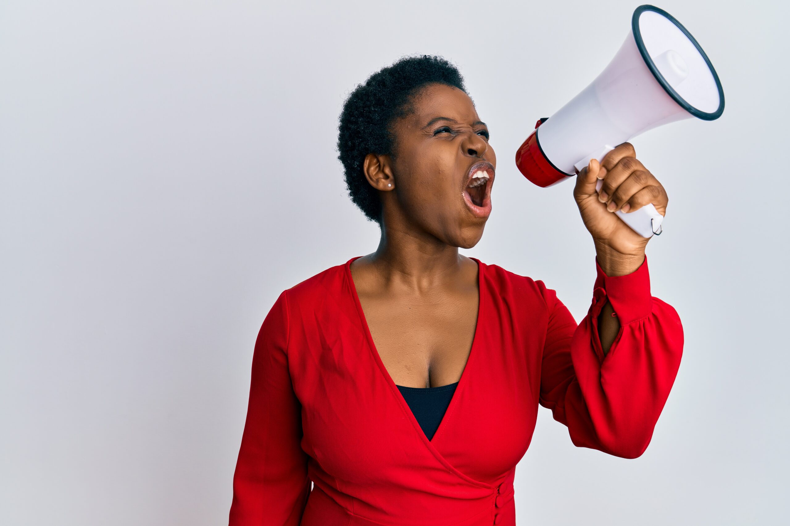 young african american woman screaming angry using megaphone over isolated white background.